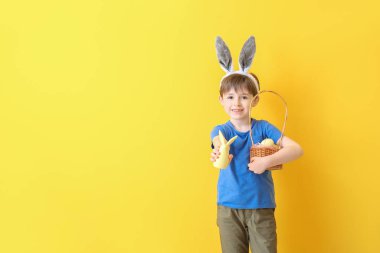 Renkli arka planda Paskalya yumurtası ve tavşanı olan küçük bir çocuk.