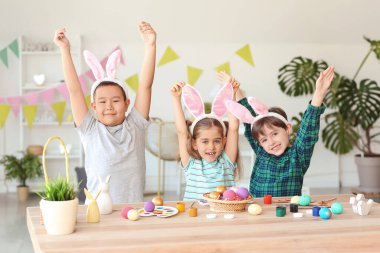 Evde boyanmış Paskalya yumurtaları ve tavşan kulakları olan küçük çocuklar.
