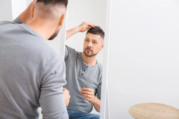 Handsome man looking in mirror at home