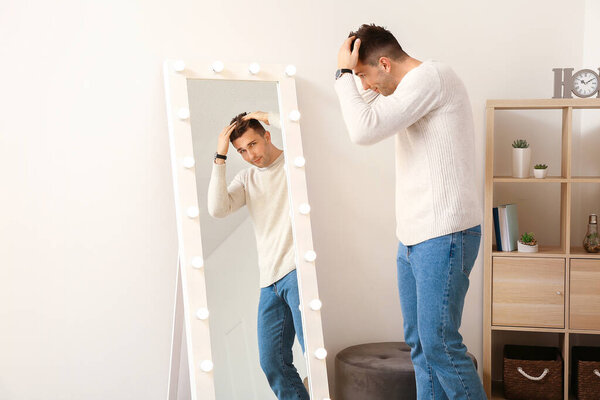 Красивый молодой человек смотрит на свое отражение в зеркале
