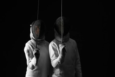 Karanlık arka planda genç eskrimciler