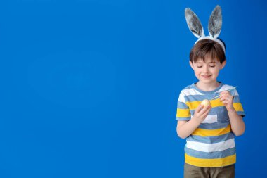 Paskalya yumurtası ve renk arkaplanı olan küçük bir çocuk.