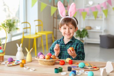 Küçük çocuk evde paskalya yumurtası boyuyor.
