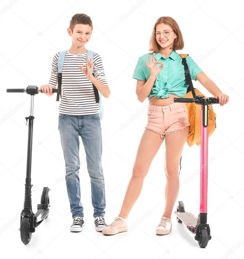 Active teenagers with kick scooters showing OK on white background