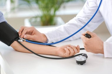 Kadın hastayı klinikte muayene eden erkek kardiyolog.