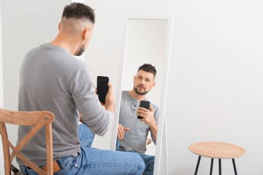 Evdeki adam aynanın önünde selfie çekiyor.