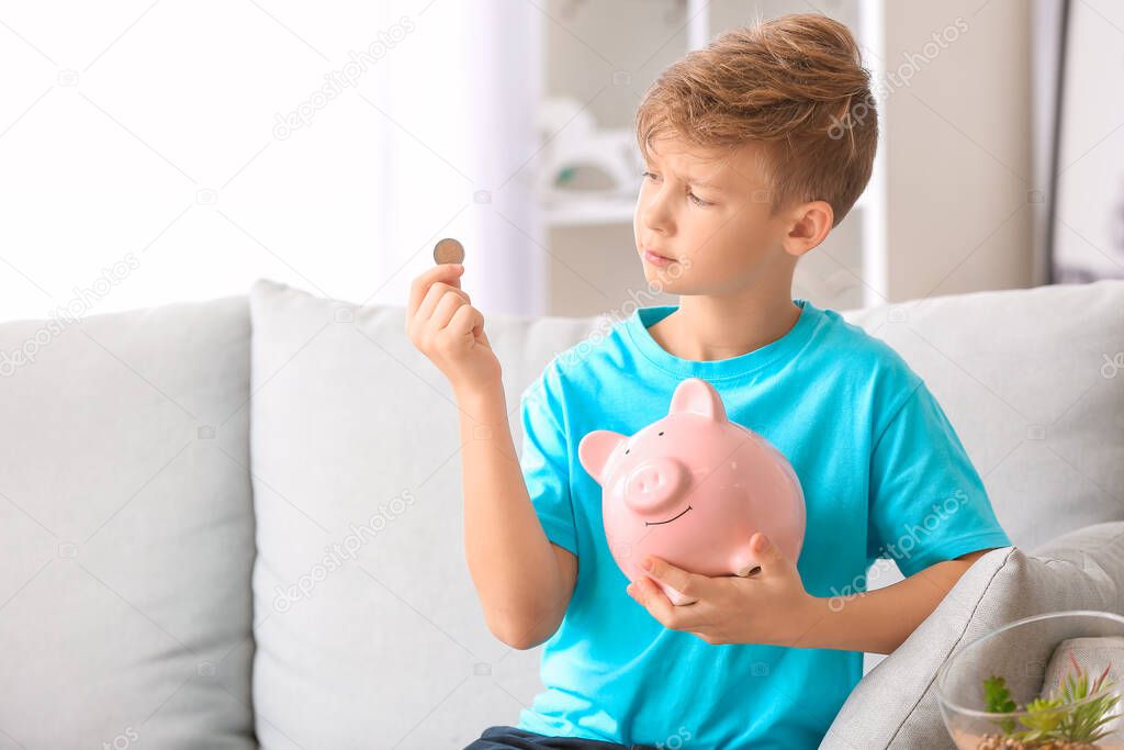 Cute boy with piggy bank and money at home