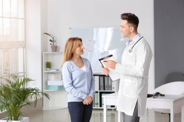 Olgun bir kadın klinikte erkek kardiyolog ziyaret ediyor.