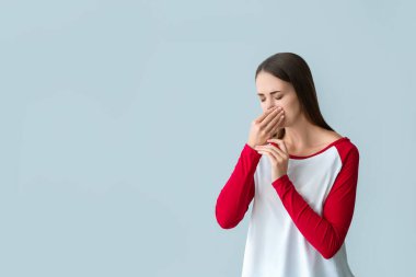 Young woman suffering from allergy on light background