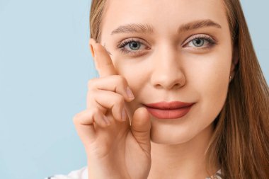 Gri arka planda kontak lensli genç kadın, yakın plan.