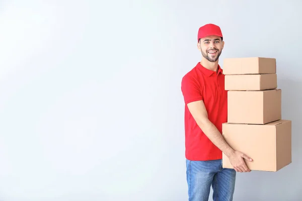 Delivery man with boxes on light background