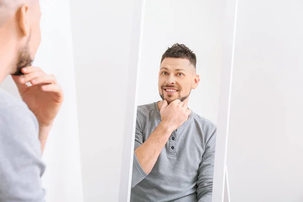 Handsome man looking in mirror at home