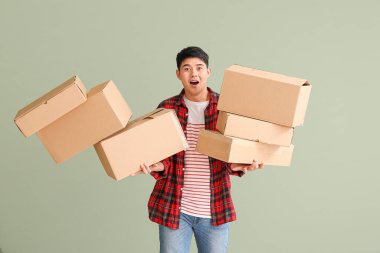 Asian man dropping moving boxes on color background clipart
