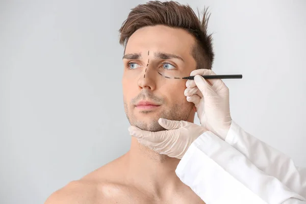 Chirurg Plastyczny Stosujący Oznakowanie Męskiej Twarzy Jasnym Tle — Zdjęcie stockowe