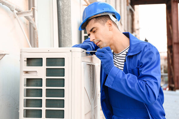 Male technician installing outdoor unit of air conditioner