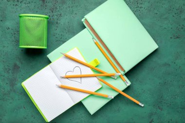 Renk arkaplanı üzerine sıradan kalemler ve defterler