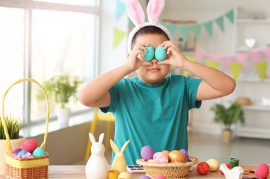 Evde boyalı Paskalya yumurtaları olan küçük Asyalı çocuk.