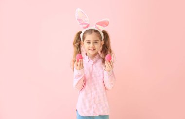 Renkli arka planda Paskalya yumurtaları ve tavşan kulakları ile küçük kız