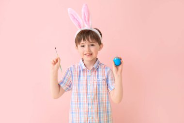 Paskalya yumurtası ve renk arkaplanı olan küçük bir çocuk.