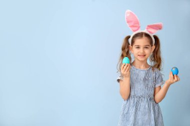 Renkli arka planda Paskalya yumurtaları ve tavşan kulakları ile küçük kız