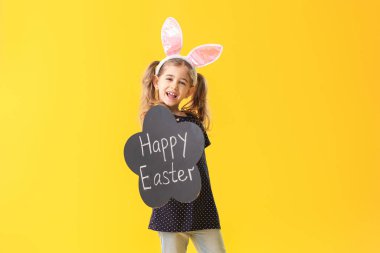 Elinde yazı tahtası olan küçük bir kız. Arka planda Mutlu Paskalyalar.