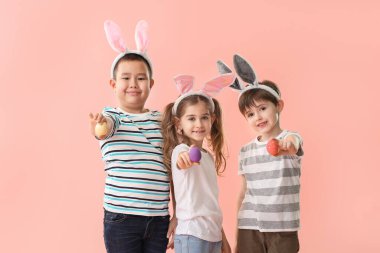Renkli arka planda Paskalya yumurtası ve tavşan kulakları ile küçük çocuklar