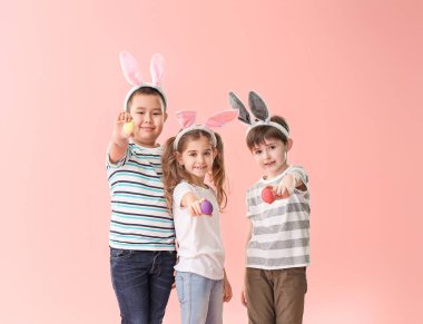 Renkli arka planda Paskalya yumurtası ve tavşan kulakları ile küçük çocuklar