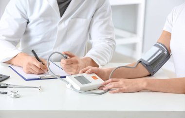 Klinikteki genç bayanın tansiyonunu ölçen doktor.