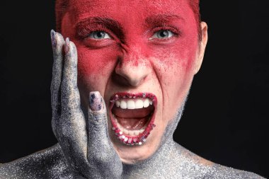 Esmer arka planda olağandışı makyajı olan güzel bir kadın.