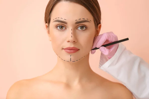 Plastik Cerrah Renk Arka Plan Karşı Kadın Yüzüne Işaretleme Uygulayarak — Stok fotoğraf