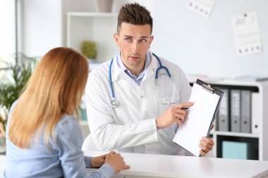 Olgun bir kadın klinikte erkek kardiyolog ziyaret ediyor.