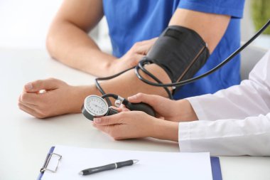 Klinikteki genç adamın tansiyonunu ölçen doktor.