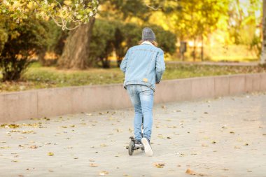 Genç adam açık havada bir tekme scooter sürme