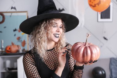 Cadılar Bayramı 'nda evde cadı gibi giyinmiş güzel bir kadın.