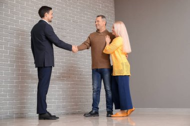 Erkek emlakçı içeride olgun bir çiftle çalışıyor.