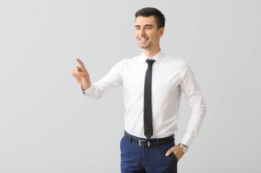 Genç işadamı gri arkaplanda sanal ekran kullanıyor