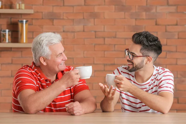 Young man and his father drinking tea in kitchen