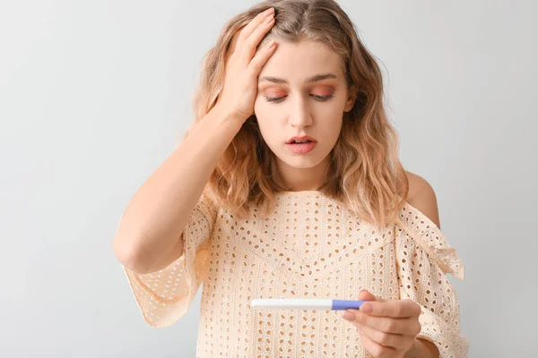 Hafif Arka Planda Hamilelik Testi Olan Üzgün Genç Bir Kadın — Stok fotoğraf