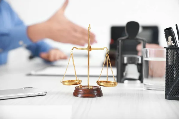 Scales of justice with mobile phone on table of notary public in office