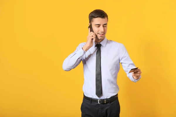 男性銀行のマネージャーとクレジットカードで話す携帯電話の色の背景 — ストック写真