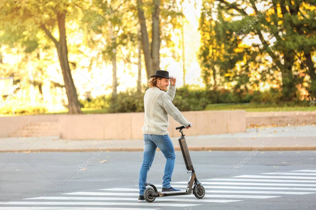 Young man riding a kick scooter outdoors