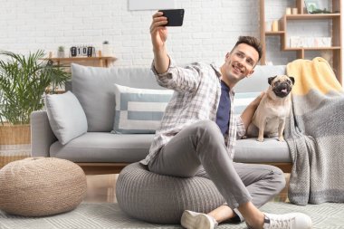 Yakışıklı adam evde sevimli bir köpekle selfie çekiyor.