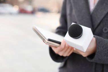 Dışarıda mikrofonlu güzel bir gazeteci, yakın plan.