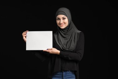 Siyah arka planda boş kağıt kağıtları olan genç bir Arap kadın.