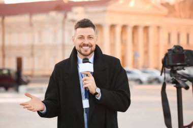 Açık havada mikrofonu olan erkek gazeteci.