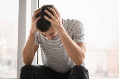 Depresyondaki genç adam pencerenin yanında