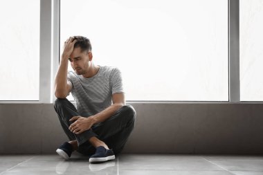 Depresyondaki genç adam pencerenin yanında
