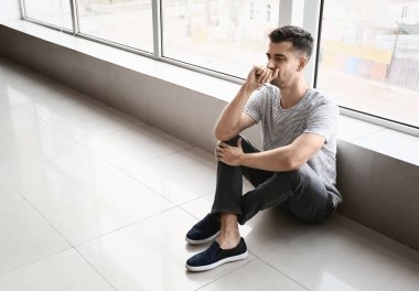 Depresyondaki genç adam pencerenin yanında