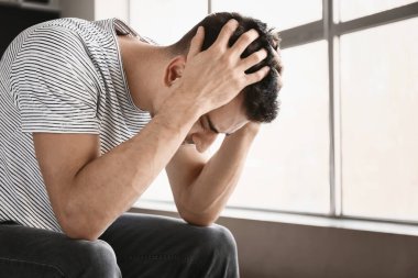 Depresyondaki genç adam pencerenin yanında