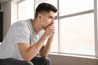 Depresyondaki genç adam pencerenin yanında
